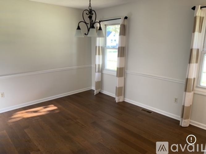 A room with wooden floors and a window with curtains.