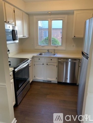 A kitchen with white cabinets and a window.