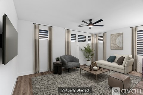 A living room with a grey couch, a grey armchair, a coffee table, and a television on the wall.