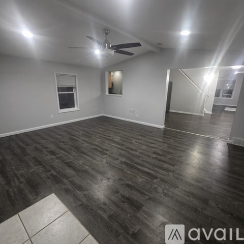 A spacious room with wooden flooring and a ceiling fan.