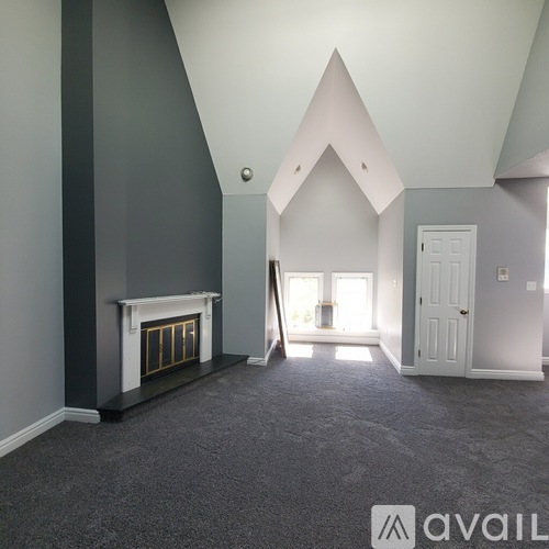 A spacious room with a fireplace and a carpeted floor.
