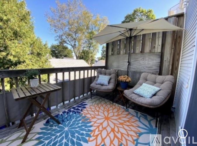 A patio with a table, chairs and a patterned rug.