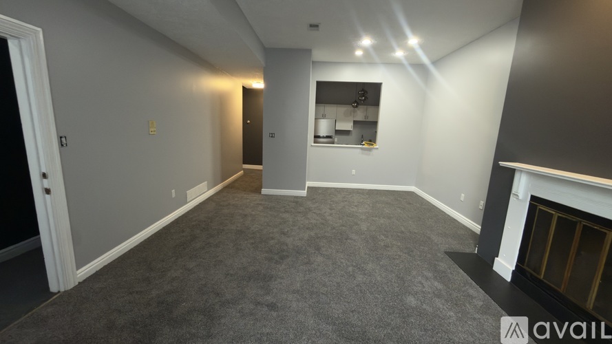 A spacious living room with a fireplace and a kitchen in the background.