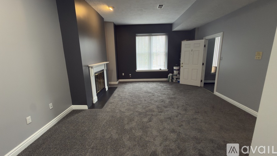 A spacious room with a fireplace and carpeted floor.
