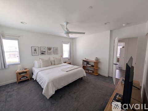 A bedroom with a large bed, a ceiling fan, and a television.