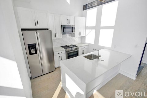 A kitchen with a refrigerator, microwave, oven, and sink.