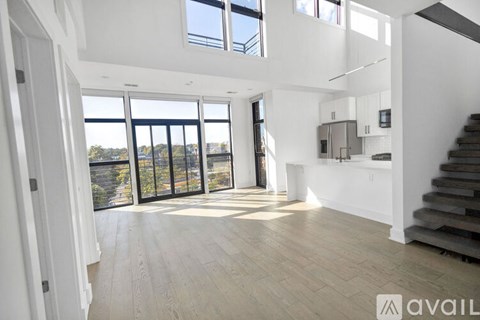 A spacious living room with a staircase on the right and a view of the outdoors through the sliding glass doors.