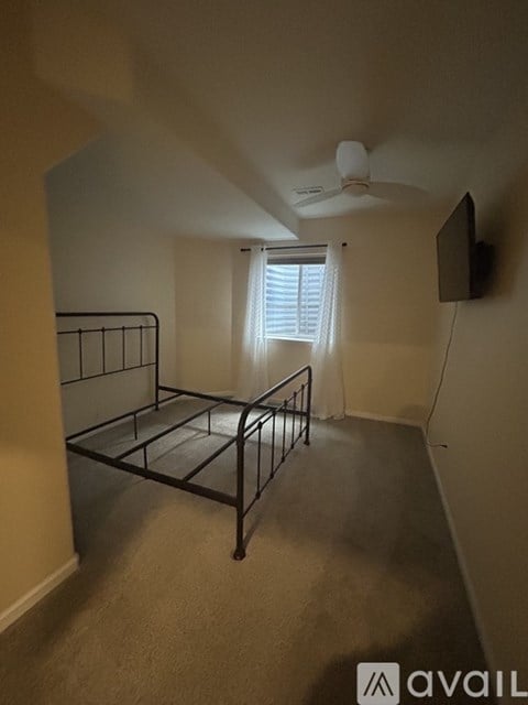 A bedroom with a bed, ceiling fan, and window.