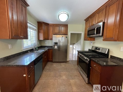 A kitchen with brown cabinets and black countertops.