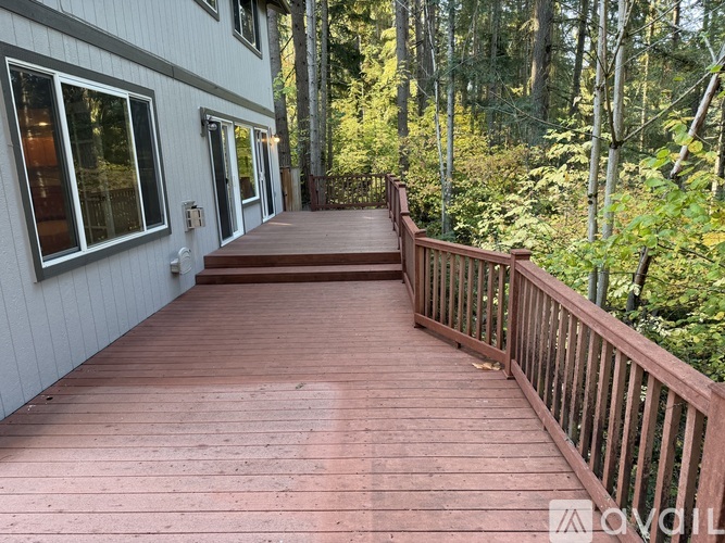 A wooden deck with a railing and a building with windows in the background.