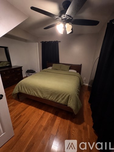 A bedroom with a bed, dresser, mirror, and ceiling fan.
