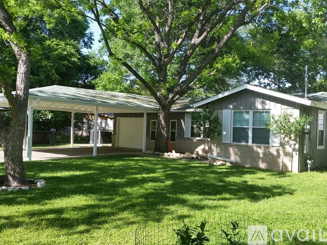 A house with a covered patio and a tree in front.