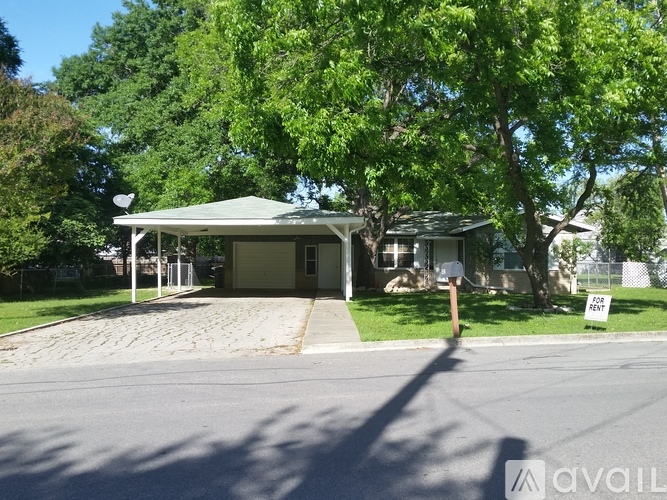 A house with a driveway and trees in front.