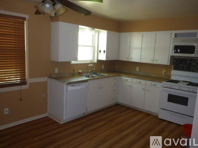 A kitchen with white appliances and wooden floors.
