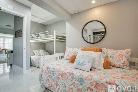 A bedroom with a floral bedspread and a round mirror on the wall.