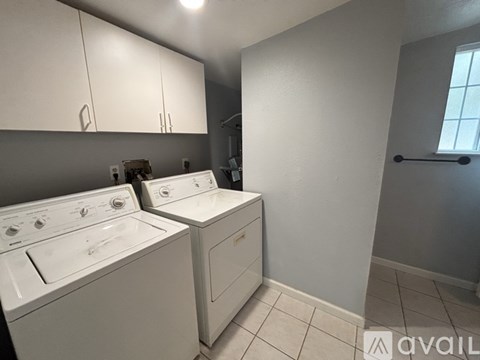 A laundry room with two washing machines and a window.