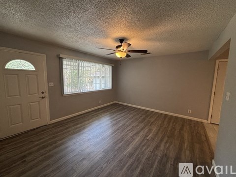 A room with a ceiling fan and wooden flooring.