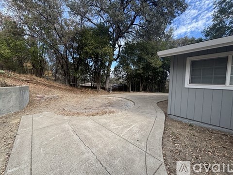 A concrete patio area with a house and trees in the background.
