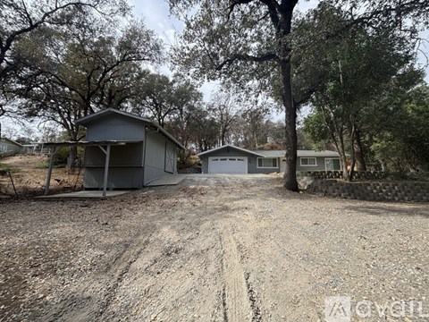 A gravel driveway leads to a two-story house with a garage.