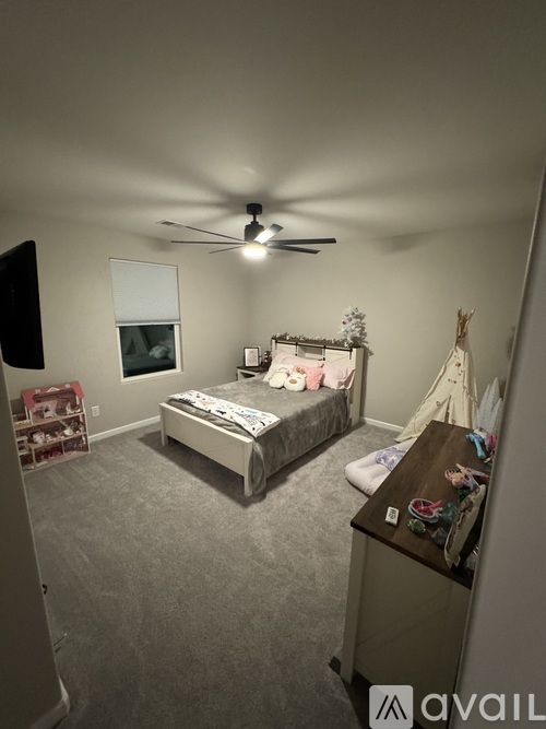 A bedroom with a bed, a ceiling fan, and a TV.