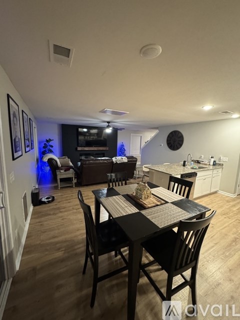 A dining room with a table set for two and a kitchen area in the background.