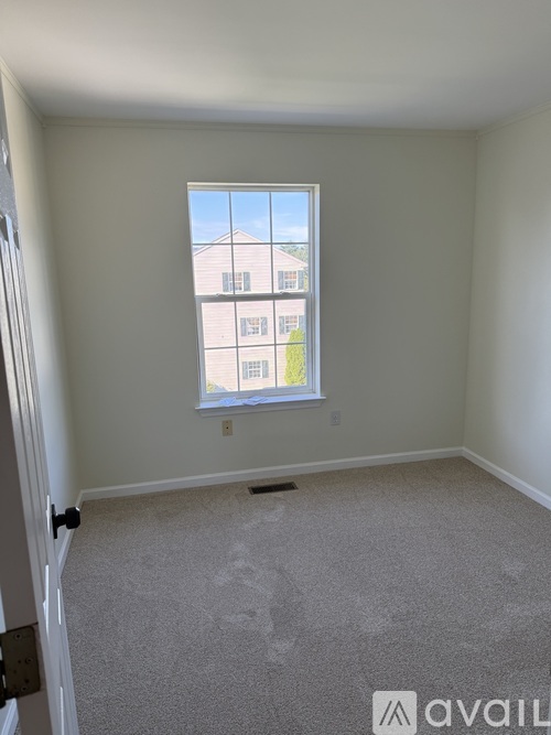 A room with a carpeted floor and a window showing a building outside.