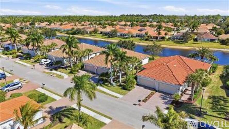 A bird's eye view of a residential area with houses, palm trees, and a body of water.