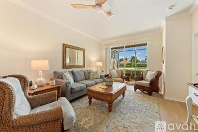 A well-lit living room with a sofa set, armchairs, and a coffee table.