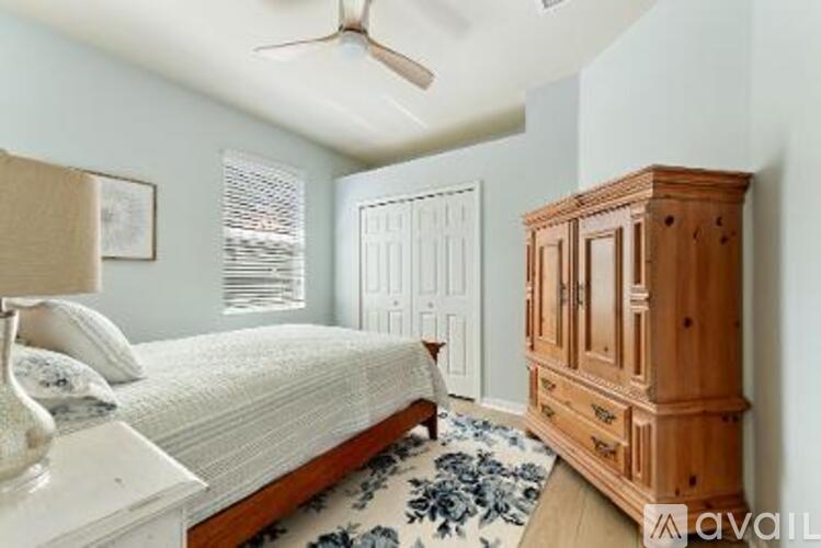 A bedroom with a bed, a dresser, and a ceiling fan.