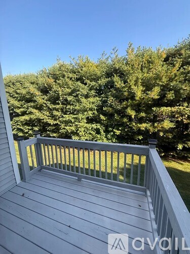 A wooden deck with a railing and trees in the background.