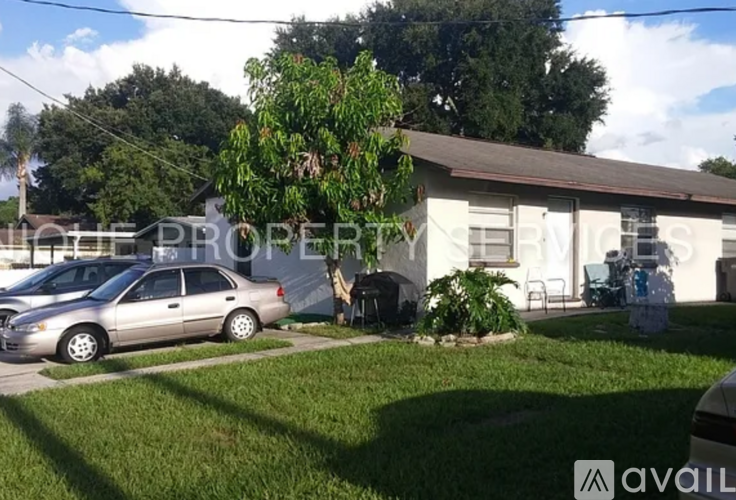 A silver car is parked in front of a house with a tree in the front yard.