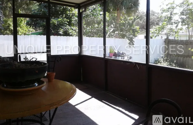 A round table with a bowl on it is in a room with a view of trees outside.