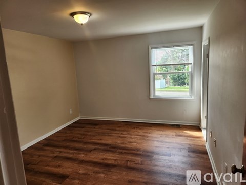 A room with wooden flooring and a window letting in natural light.