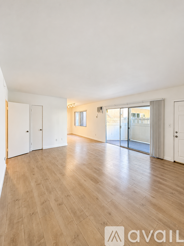 A spacious room with wooden flooring and white walls.