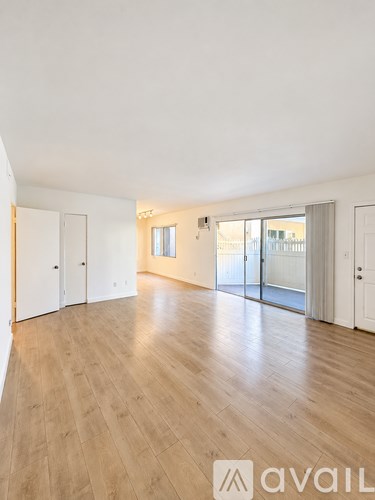 A spacious room with wooden flooring and white walls.