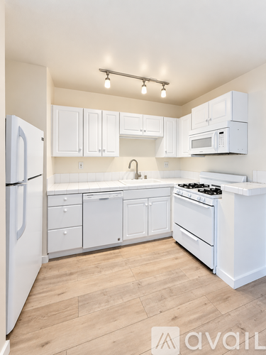 A white kitchen with wooden floors and white appliances.