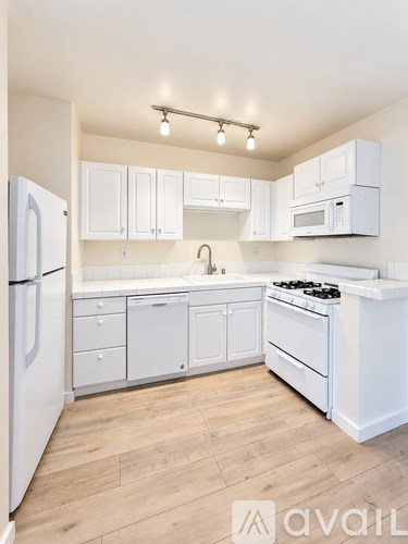A white kitchen with wooden floors and white appliances.