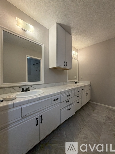 A bathroom with a sink, mirror, and cabinets.