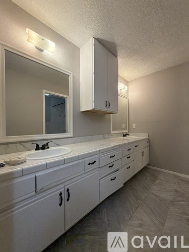 A bathroom with a sink, mirror, and cabinets.