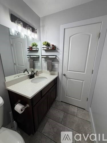 A bathroom with a sink, toilet, and a mirror.