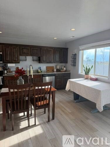 A kitchen with wooden chairs and a table with a white tablecloth.