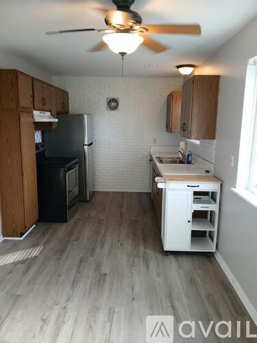 A kitchen with a black fridge and wooden cabinets.
