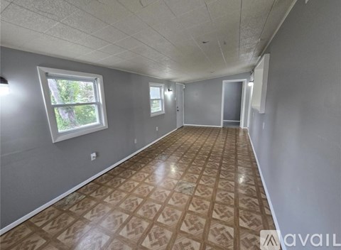 A room with a patterned floor and two windows.