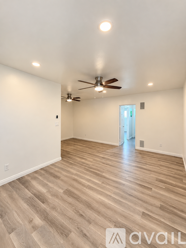 A room with a ceiling fan and wooden flooring.