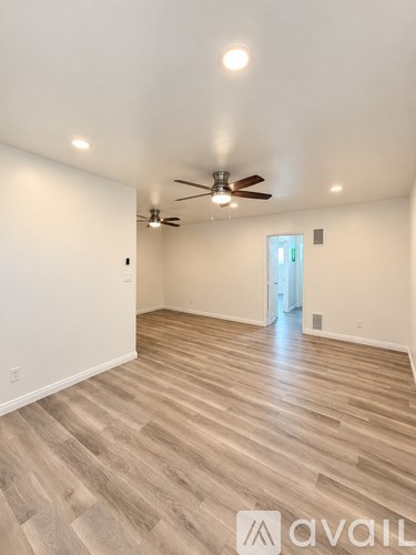 A room with a ceiling fan and wooden flooring.