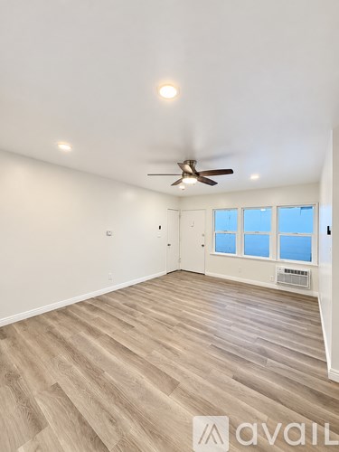A room with a ceiling fan and wooden flooring.