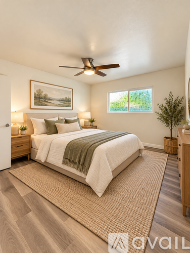 A bedroom with a bed, a ceiling fan, and a painting on the wall.