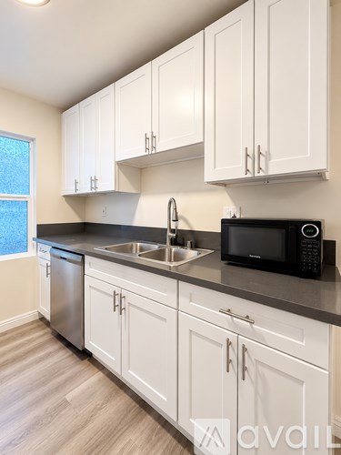 A kitchen with white cabinets and a black microwave.