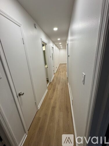 A long hallway with white walls and wood flooring.