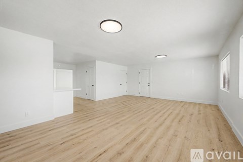 A spacious room with wooden flooring and white walls.
